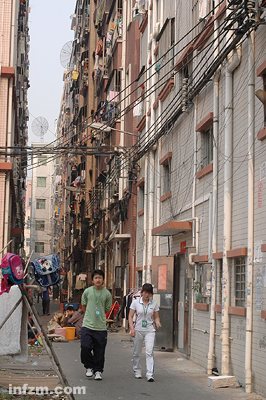 从出租屋里走出来的打工族。出租屋楼群之间的电线、网线、电话线胡乱牵搭着。他们的青春就生活在这样的空间里。 (南方周末记者 王轶庶/图)